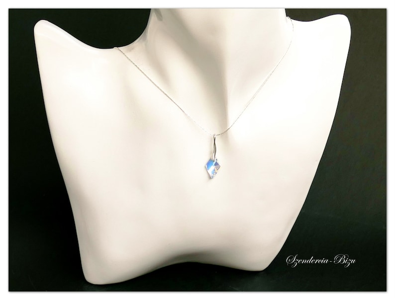 May include: A silver chain necklace with a clear crystal pendant. The pendant is faceted and has a slight iridescent shimmer.