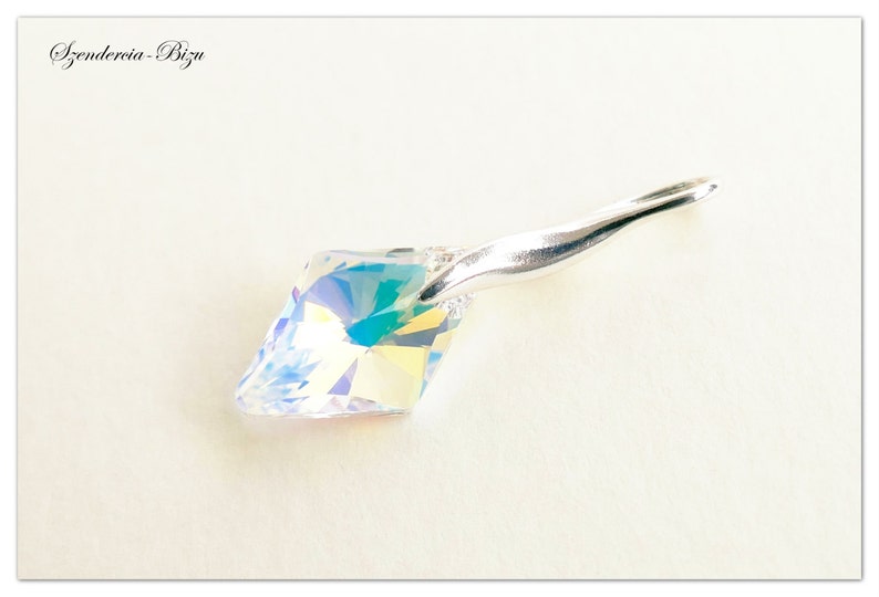 May include: A silver pendant with a clear iridescent crystal. The crystal is faceted and has a rainbow effect. The pendant is on a white background.