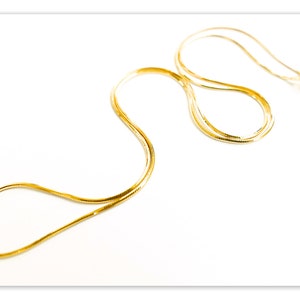 Puede incluir: Un collar de cadena de oro con un diseño de cadena de serpiente.