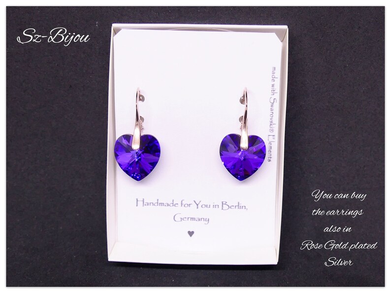May include: A pair of silver heart-shaped earrings with purple crystals. The earrings are made with Swarovski elements and are handmade in Berlin, Germany. You can also buy the earrings in rose gold plated silver.