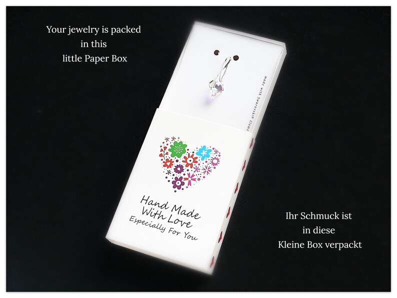 May include: A white paper box with a red dotted border. The box has a heart-shaped design with colorful flowers inside. The text on the box reads "Hand Made With Love Especially For You".