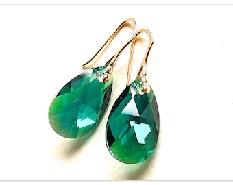 Pode incluir: Um par de brincos de argola de ouro com pedras de cristal em forma de lágrima de cor verde esmeralda.