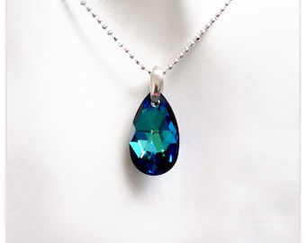Pode incluir: Um colar de corrente de prata com um pingente em forma de lágrima. O pingente é de cor azul escuro com acentos iridescentes verdes e azuis.