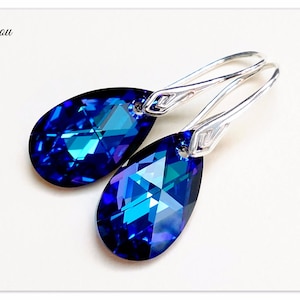 Pu&ograve; includere: Un paio di orecchini pendenti in argento con pietre di cristallo blu a forma di goccia. I cristalli hanno un design sfaccettato e brillano alla luce.