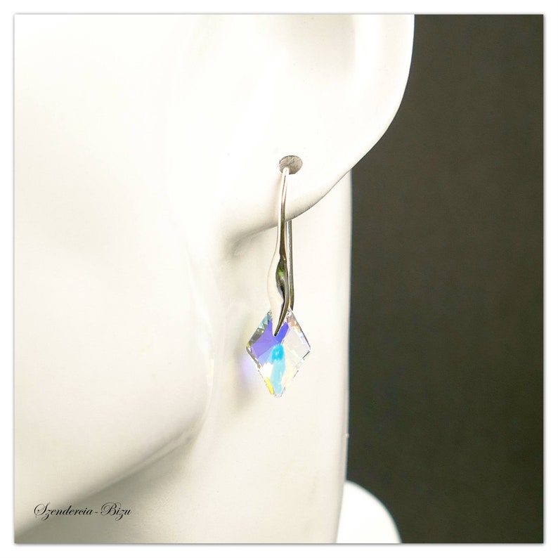 May include: Silver dangle earrings with a clear iridescent square crystal.