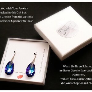 Pu&ograve; includere: Un paio di orecchini a forma di goccia con accenti di cristallo blu e viola. Gli orecchini sono confezionati in una scatola regalo bianca con il testo "Shiver" sulla parte superiore. Il testo "If You wish Your Jewelry packed in this Gift Box, please Choose from the Options Your selected Option with "Box"" &egrave; visibile nell'angolo in alto a sinistra dell'immagine.