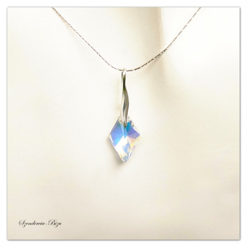 May include: A silver chain necklace with a clear iridescent crystal pendant in a square shape.