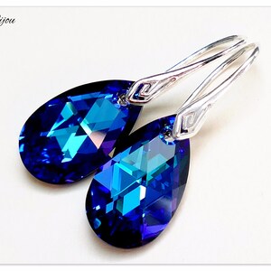 Pu&ograve; includere: Un paio di orecchini pendenti in argento con cristalli blu a forma di goccia. I cristalli hanno un colore blu intenso con un tocco di verde.