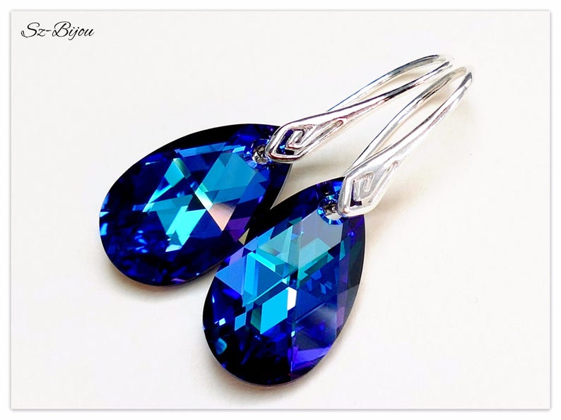 Pu&ograve; includere: Un paio di orecchini pendenti in argento con cristalli blu a forma di goccia. I cristalli hanno un colore blu intenso con un tocco di verde.