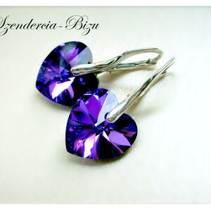 May include: A pair of silver heart-shaped earrings with purple crystal accents. The earrings have a hook closure.