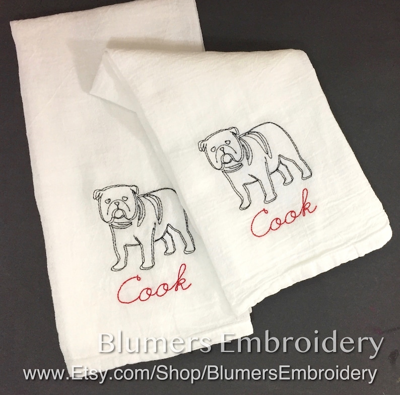 Monogrammed Bulldog Kitchen Dish Towel Personalized Dog Gift Custom Pet Flour Sack Tea Towel  Hostess Gift Personalized Bulldog Gift: Two white kitchen towels with black embroidered bulldog illustrations and the word 'Cook' in red embroidery. The towels are folded and displayed on a black background. The text 'Blumers Embroidery' and 'www.Etsy.com/Shop/BlumersEmbroidery' is visible at the bottom of the image.