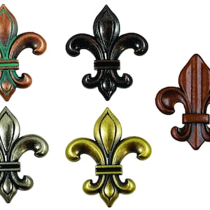 May include: Five decorative fleur-de-lis in different finishes: copper with green accents, black, brown, silver, and gold.