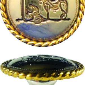 May include: A gold-toned metal knob with a black center and a rope-like design around the edge. The knob features a raised image of a horse and a cross.