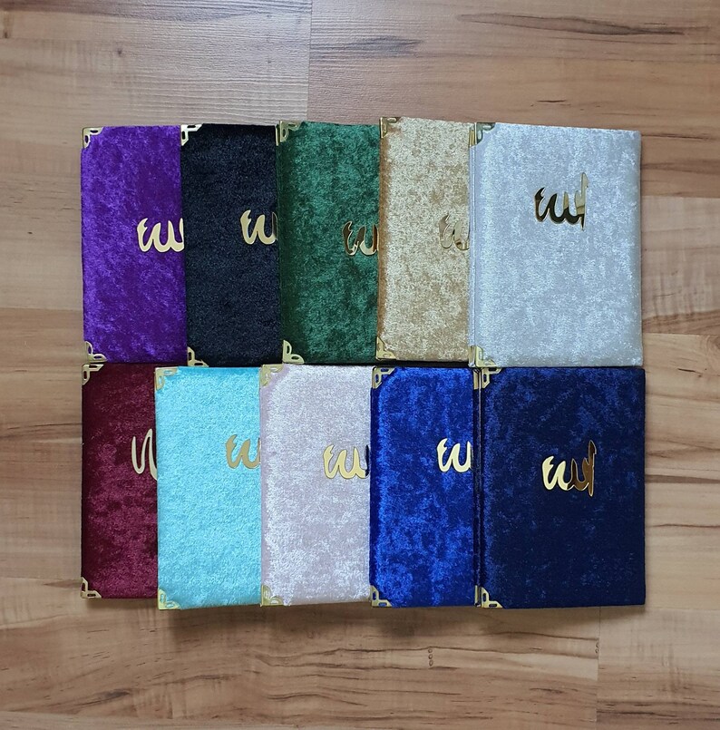 May include: Ten velvet-covered journals with gold accents and the Arabic word for God, "Allah", written in gold on the front. The journals are in various colors, including purple, black, green, gold, silver, maroon, light blue, beige, blue, and navy.