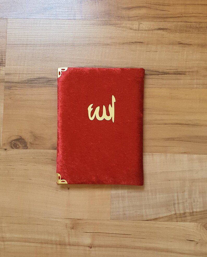 May include: A red velvet book cover with gold corners and the word "الله" in gold lettering.