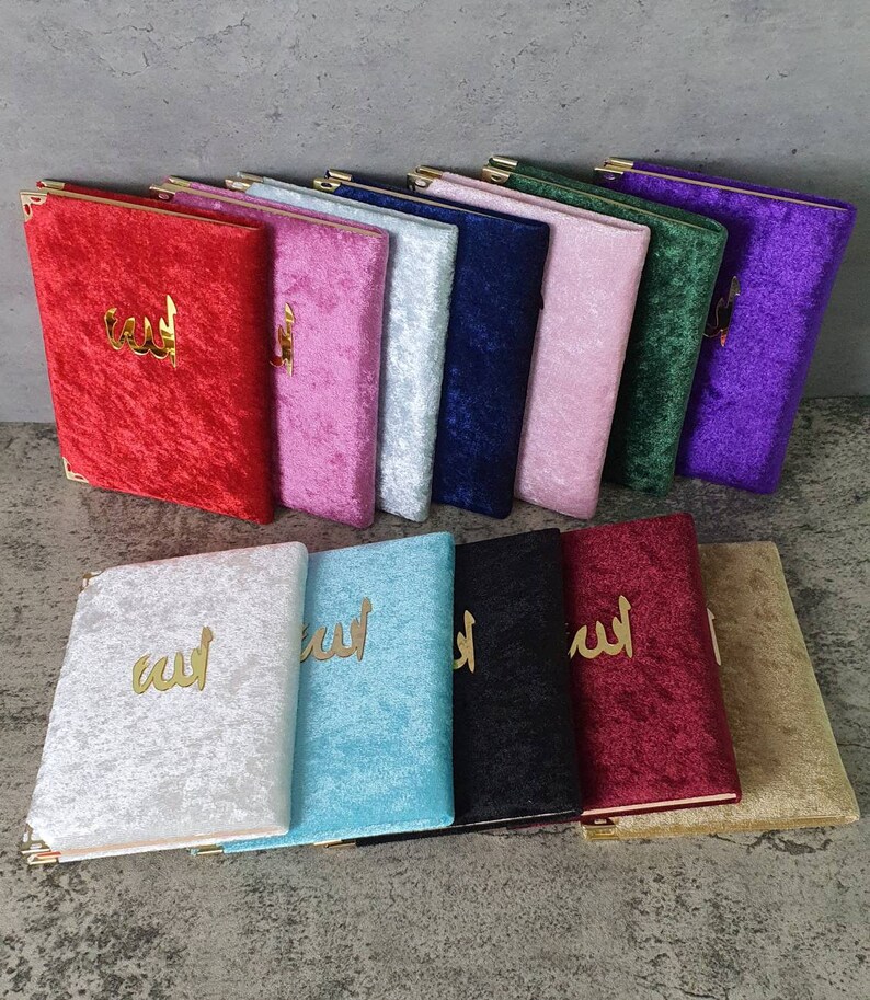 May include: A collection of 12 velvet-covered notebooks with gold lettering. The notebooks are in various colors, including red, pink, blue, green, purple, white, and turquoise. The notebooks feature the Arabic word for "God" in gold lettering.