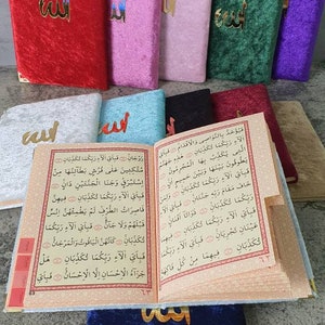 May include: A set of colorful velvet covers for a Quran, featuring the Arabic word "Allah" in gold lettering. The covers are in red, pink, light pink, green, purple, light blue, black, and dark blue.