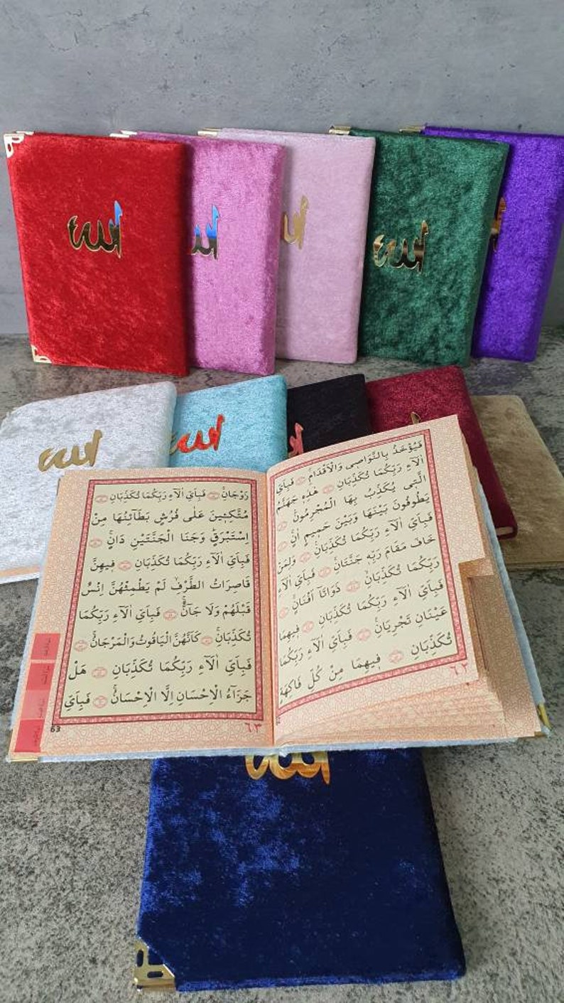 May include: A set of colorful velvet covers for a Quran, featuring the Arabic word "Allah" in gold lettering. The covers are in red, pink, light pink, green, purple, light blue, black, and dark blue.