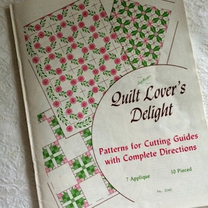 May include: A vintage quilt pattern book titled "Quilt Lover's Delight." The cover displays floral and geometric quilt block designs in pink and green. The book includes patterns for cutting guides with complete directions, 7 applique, and 10 pieced designs.