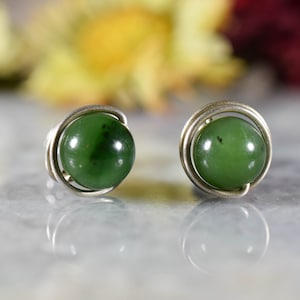 Puede incluir: Un par de pendientes de alambre plateado con cuentas de jade verde.