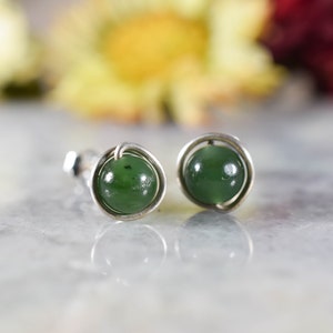 May include: A pair of silver earrings with green jade stones set in a wire frame.