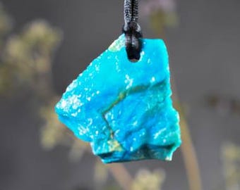 May include: A turquoise blue pendant made from a natural stone, hanging from a black cord.
