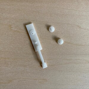 Puede incluir: Pestillo de pl&aacute;stico blanco con una manija larga y delgada y dos peque&ntilde;os pomos redondos.