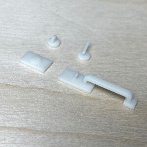 Puede incluir: Cuatro piezas de herrajes de puerta en miniatura de pl&aacute;stico blanco, que incluyen una manija de puerta, un pomo de puerta y dos topes de puerta.