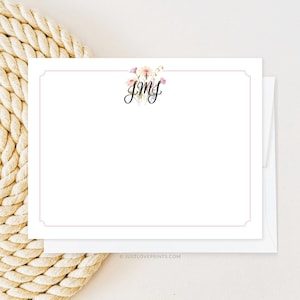 May include: A white card with a pink and white floral design and the monogram "JMG" in black script. The card has a thin pink border.