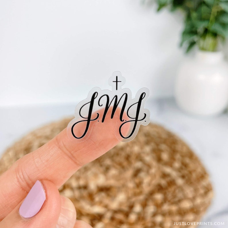 Clear JMJ with cross written in black letters on a finger