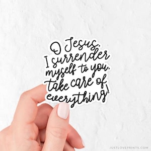 May include: A white die-cut sticker featuring black cursive lettering that reads, O Jesus. I surrender myself to you. take care of everything! The sticker has a clean, simple design with a white border and a smooth, matte-like finish.