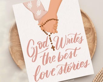 May include: A white rectangular print featuring an illustration of two hands holding a brown beaded rosary with a cross. The text "God Writes the best love stories" is written in a pink cursive script below the hands. The print has a textured finish.