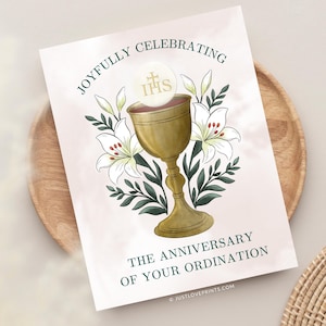 May include: A rectangular card featuring a gold chalice and a white communion wafer with the letters IHS. The illustration includes white lilies with green leaves and the text JOYFULLY CELEBRATING THE ANNIVERSARY OF YOUR ORDINATION in dark green.