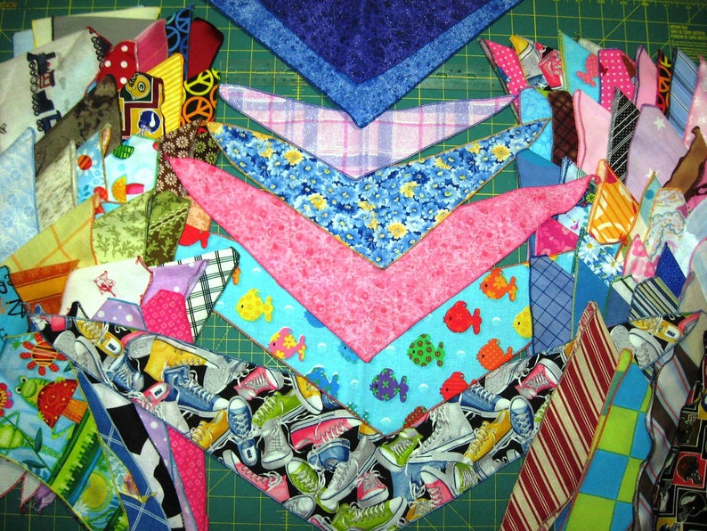 Peut inclure: Un assortiment de chutes de tissu color&eacute;es dispos&eacute;es en motif sur un tapis de coupe vert. Les chutes sont de formes et de tailles vari&eacute;es, et certaines pr&eacute;sentent des motifs ou des dessins. Les chutes sont dispos&eacute;es de mani&egrave;re &agrave; sugg&eacute;rer qu'elles sont pr&eacute;par&eacute;es pour un projet de courtepointe.