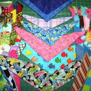 May include: A collection of colorful fabric scraps in various patterns and designs, including floral, geometric, and animal prints. The scraps are arranged in a fan shape, with the largest scrap at the top and the smallest scraps at the bottom. The scraps are all cut into a triangular shape.