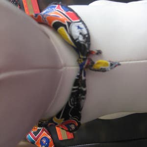 Peut inclure: Un mannequin en tissu blanc avec une &eacute;charpe &agrave; motifs color&eacute;s nou&eacute;e autour du cou. L'&eacute;charpe a un fond noir avec des accents orange, jaune, bleu et rouge. L'&eacute;charpe est nou&eacute;e en un n&oelig;ud &agrave; l'avant du cou du mannequin.
