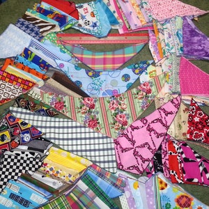 Peut inclure: Une collection de bandanas en tissu color&eacute;s avec diff&eacute;rents motifs, notamment des imprim&eacute;s g&eacute;om&eacute;triques, floraux et animaliers. Les bandanas sont dispos&eacute;s en &eacute;ventail sur une surface verte.