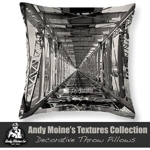 May include: Black and white photograph of a metal bridge. The bridge is made of steel beams and has a long, narrow walkway. The photograph is taken from the perspective of someone standing on the walkway, looking towards the other end of the bridge.