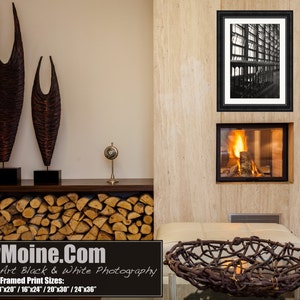 K&ouml;nnte beinhalten: Ein Schwarzwei&szlig;foto eines Geb&auml;udes mit modernem Design ist gerahmt und an einer Wand &uuml;ber einem Kamin angebracht. Der Kamin ist angez&uuml;ndet und hat einen Stapel Holzscheite davor. Auf einem Regal &uuml;ber dem Kamin stehen zwei Holzskulpturen.
