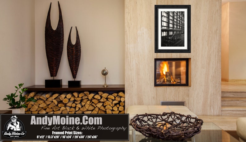 K&ouml;nnte beinhalten: Ein Schwarzwei&szlig;foto eines Geb&auml;udes mit modernem Design ist gerahmt und an einer Wand &uuml;ber einem Kamin angebracht. Der Kamin ist angez&uuml;ndet und hat einen Stapel Holzscheite davor. Auf einem Regal &uuml;ber dem Kamin stehen zwei Holzskulpturen.