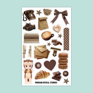 Könnte beinhalten: Ein Stickerbogen mit braun getönten Illustrationen. Er zeigt ein Vintage-Telefon, Schuhe, Bücher, eine Kaffeetasse, einen Teddybären, eine Schleife, einen herzförmigen Knopf, ein Croissant und eine Puppe, die einen Keks hält. Der Text "MORGAN REVEAL STUDIOS" befindet sich unten.