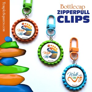 May include: Bottlecap zipper pull clips in orange, green, and blue. Each clip features a circular design with the text "Walk with Me" and a footprint and mountain graphic. The clips have a metal ring and a carabiner-style clip.
