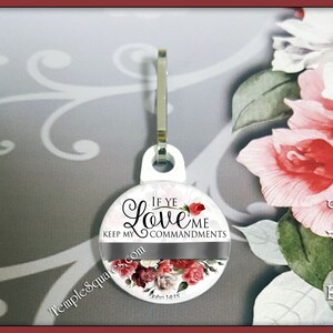 May include: White round zipper pull with a floral design and the text "If ye love me keep my commandments John 14:15".
