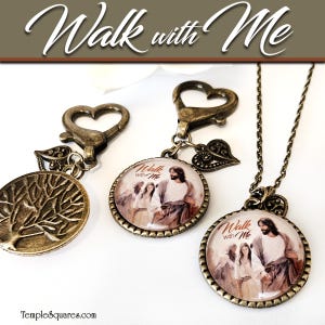 May include: Three antique bronze-toned pendants and keychains. One features a tree of life design, another a circular image of Jesus with the text "Walk with Me", and the third is a necklace with the same image. All have heart-shaped clasps.