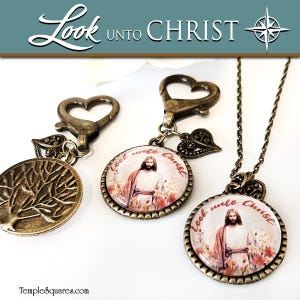 May include: Two bronze keychains with a heart-shaped clasp and a round charm featuring a picture of Jesus Christ. The charms have the text "Look unto Christ" on them. One keychain also has a tree-shaped charm.