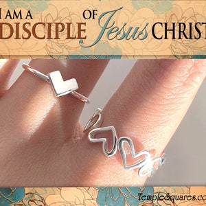 May include: Two silver rings on a finger. One ring has a square heart shape and the other has a series of connected heart shapes. The background is a floral pattern with the text "I am a disciple of Jesus Christ".