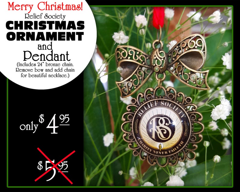May include: A gold-toned Christmas ornament with a decorative bow and a round pendant featuring the text "Relief Society Charity Never Faileth". The pendant has a black and gold design with the letters "RS" in the center.