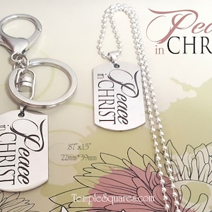 May include: Silver keychain and necklace with a silver dog tag pendant that reads "Peace in Christ". The dog tag is 0.87 inches by 1.5 inches or 22 millimeters by 39 millimeters.