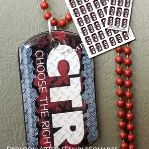 Puede incluir: Una placa de identificación de perro de metal roja y blanca con las palabras "CTR CHOOSE THE RIGHT" impresas en ella. La placa de identificación de perro está unida a un collar de cuentas rojas. La imagen también incluye una hoja de pegatinas imprimibles con la palabra "CTR" en cada pegatina.