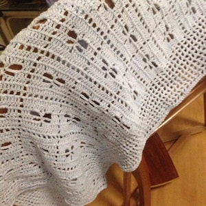 May include: A light blue crocheted baby blanket with a delicate openwork pattern.